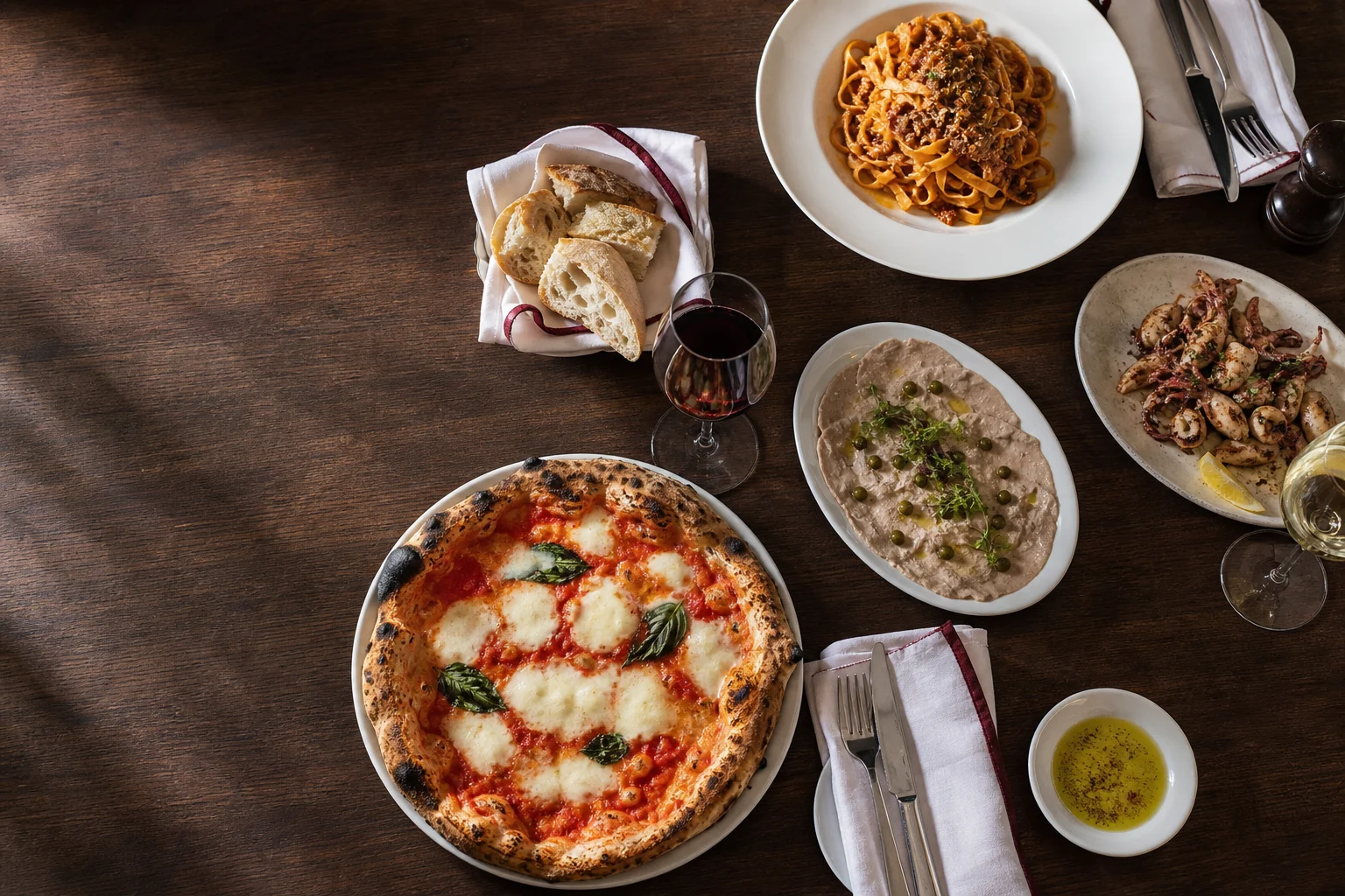 Repräsentativ gedeckter italienischer Tisch mit Pizza, Pasta und Antipasti